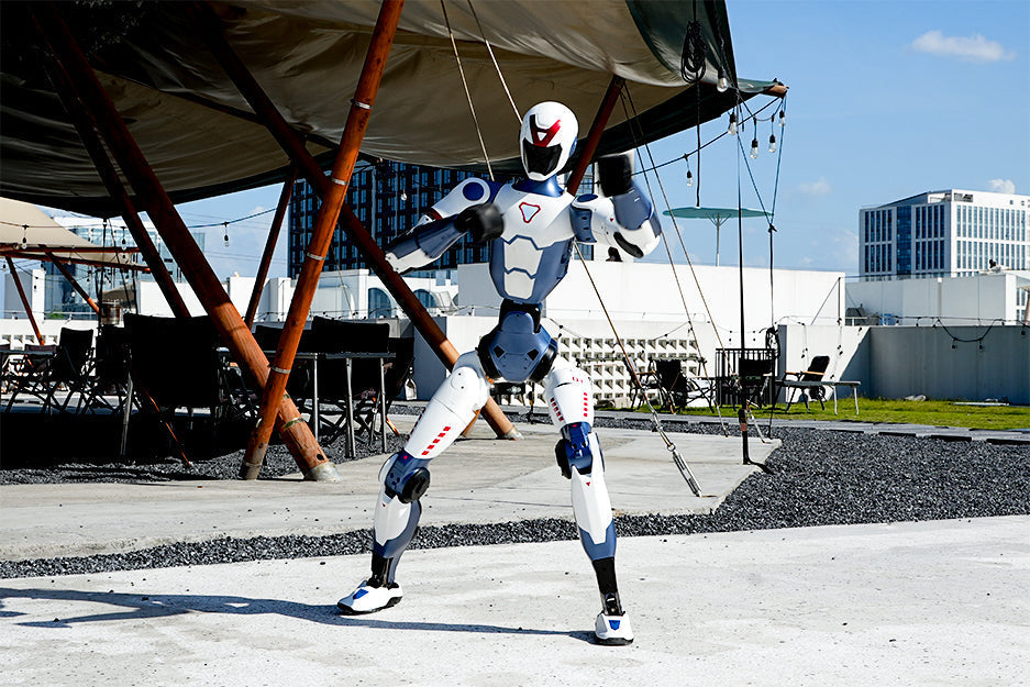 Unitree R1 Humanoid boxing mode and standing in front of an old airplane with modern buildings in the background.