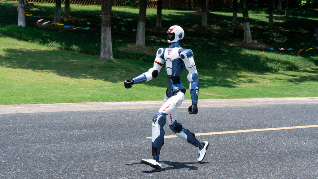 Unitree R1 Robot walking on a road with trees and grass in the background